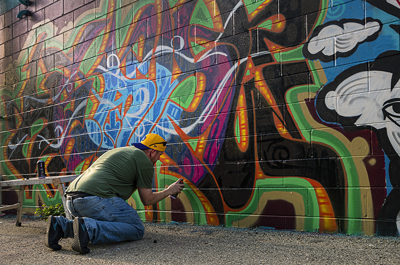 Man kneeling and painting a wall.