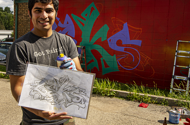 Street artist holding his sketch of what he is painting.